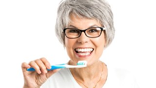 Smiling woman with toothbrush and dental implants in Lakeville