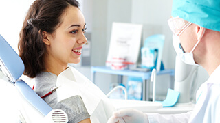 Woman in dental chair talking to dentist