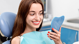 Woman looking at flawless smile in mirror