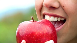 Closeup of patient with dental implants in Lakeville eating an apple