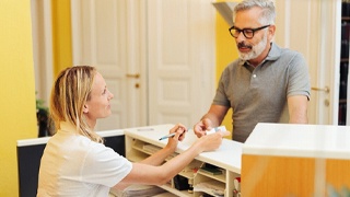 Mature man paying for treatment after emergency appointment