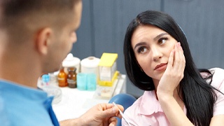 Woman with toothache talking to dentist