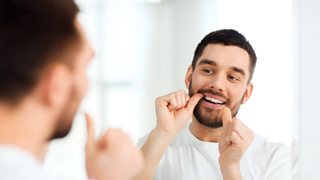 Man flossing his dental implants in Lakeview