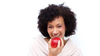 woman with dental implants in Lakeville eating an apple