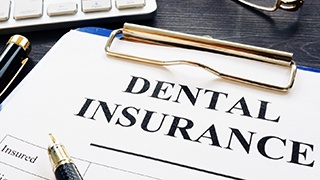 Dental insurance form on clipboard next to keyboard