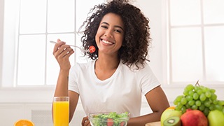 Woman in white t-shirt eating salad with orange juice
