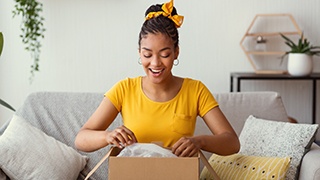 Woman in yellow shirt on couch opening box