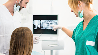 Patient and dental team looking at dental x-rays