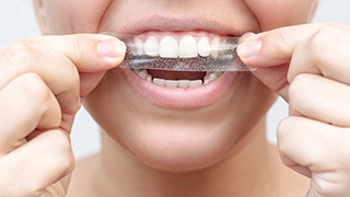 Person applying teeth whitening strip