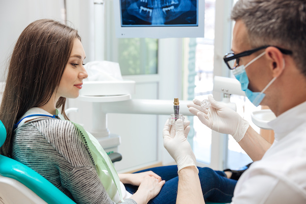 Dentist showing patient dental implant in office