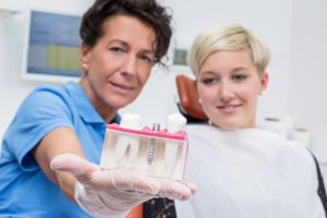 Dentist showing patient a dental implant model