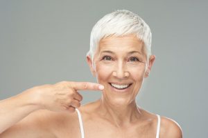 Smiling senior woman enjoying the natural feel of dental implants