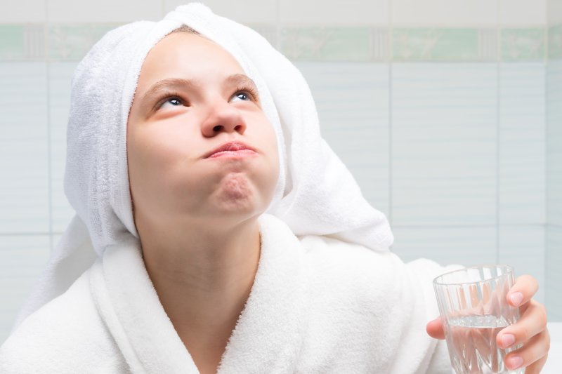 young woman rinsing after brushing teeth 