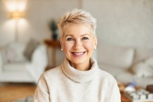 Older woman smiling while wearing a cream sweater