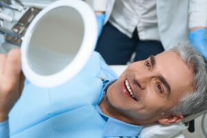 Middle-aged dental patient admiring his smile in mirror