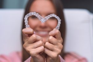 Woman holding two SureSmile aligners in heart shape